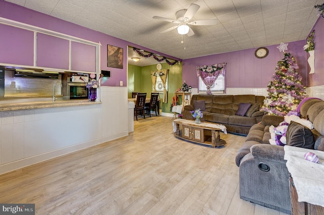 living area featuring light wood-style flooring and a ceiling fan