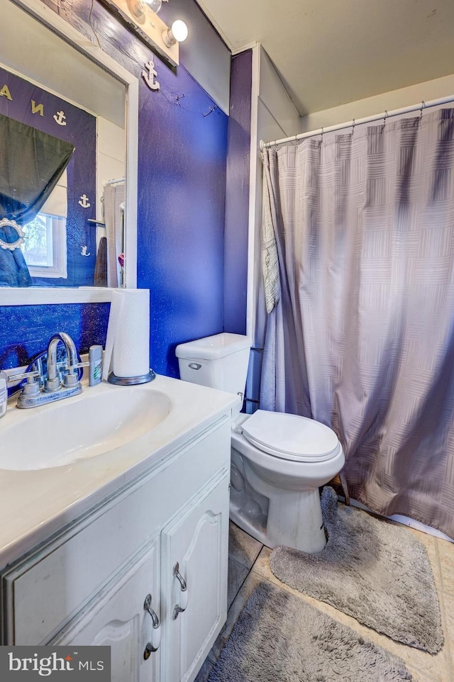 bathroom with curtained shower, vanity, toilet, and tile patterned floors