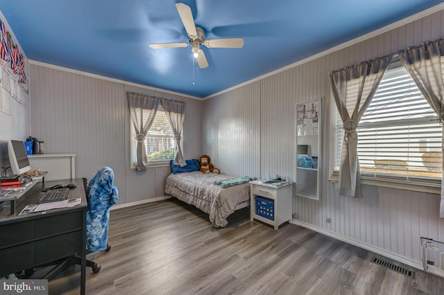 bedroom with baseboards, visible vents, wood finished floors, and ornamental molding