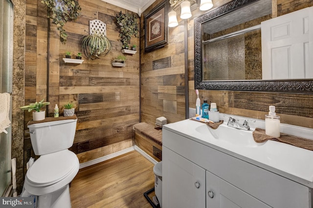 bathroom with toilet, wood walls, vanity, wood finished floors, and tiled shower