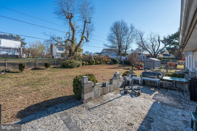 view of yard with an outbuilding, a patio, fence, and a shed