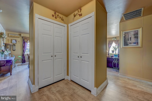 foyer with light wood finished floors, baseboards, and visible vents