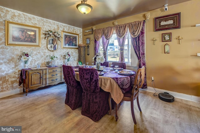 dining room featuring wallpapered walls, baseboards, and light wood-style floors