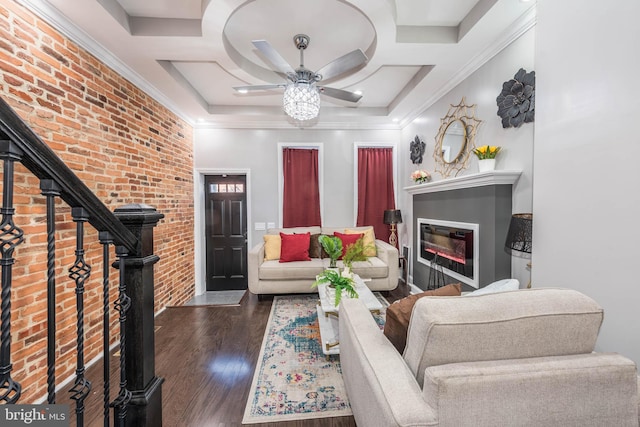 living room with ceiling fan, a tray ceiling, dark hardwood / wood-style floors, and brick wall