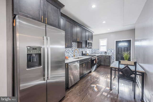 kitchen with decorative backsplash, appliances with stainless steel finishes, dark brown cabinets, dark wood-type flooring, and sink