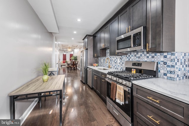 kitchen with light stone countertops, sink, tasteful backsplash, dark hardwood / wood-style floors, and appliances with stainless steel finishes