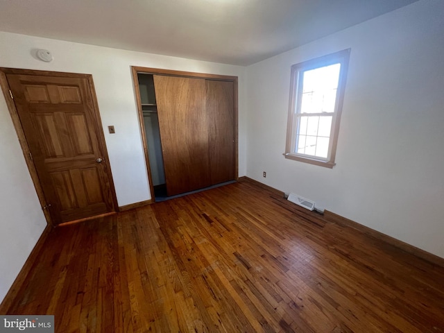 unfurnished bedroom with a closet and dark wood-type flooring