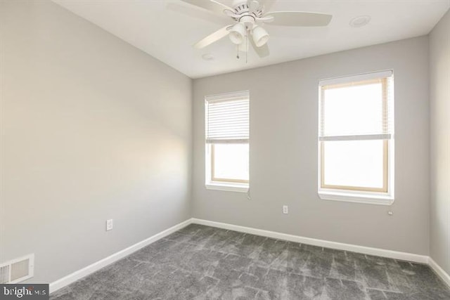 spare room featuring dark colored carpet, a wealth of natural light, and ceiling fan