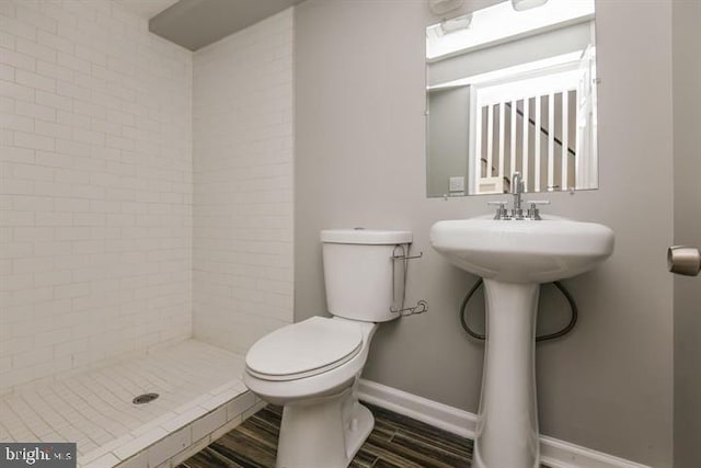 bathroom with a tile shower, hardwood / wood-style floors, and toilet