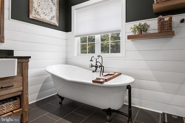 bathroom with tile patterned floors, a bathtub, and wood walls