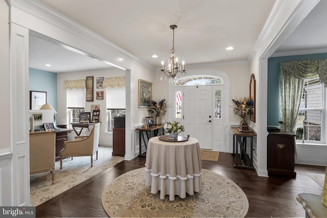 entrance foyer with dark hardwood / wood-style flooring, crown molding, a notable chandelier, and a healthy amount of sunlight