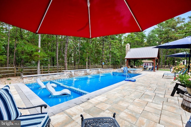 view of pool with an outbuilding, a patio area, pool water feature, an in ground hot tub, and a gazebo