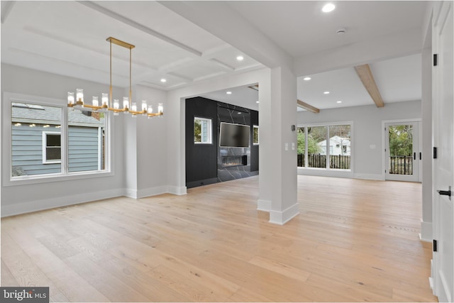 interior space featuring beam ceiling, a fireplace, light hardwood / wood-style floors, and a notable chandelier