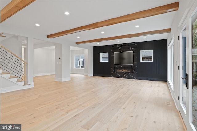 unfurnished living room with beam ceiling and light hardwood / wood-style floors