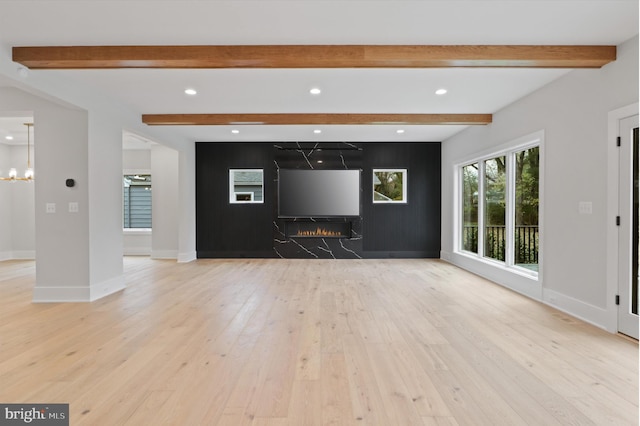 unfurnished living room with beam ceiling and light hardwood / wood-style floors