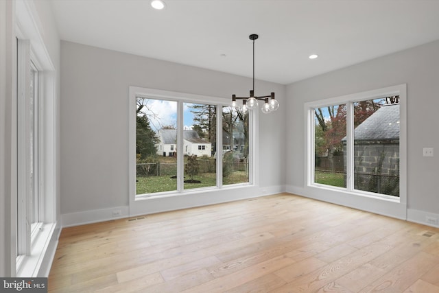 unfurnished dining area featuring light hardwood / wood-style floors and a notable chandelier