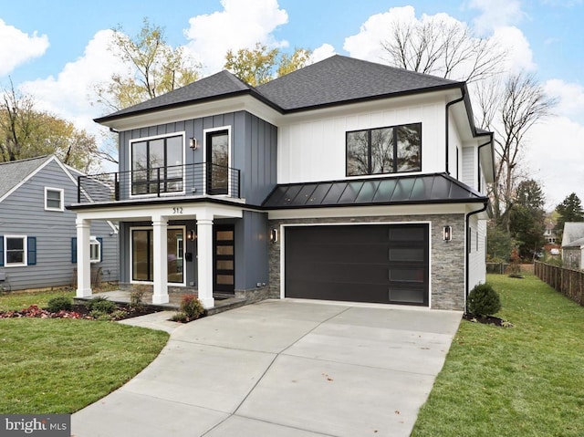 view of front of property featuring covered porch, a balcony, a garage, and a front lawn