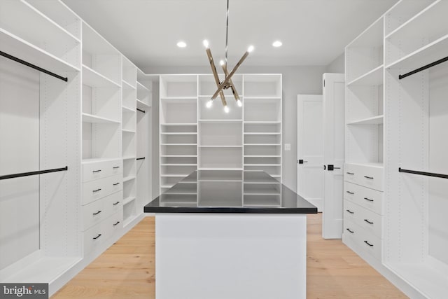 spacious closet featuring an inviting chandelier and light hardwood / wood-style flooring