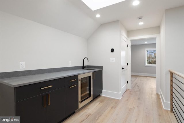 kitchen with vaulted ceiling, light hardwood / wood-style flooring, wine cooler, and sink