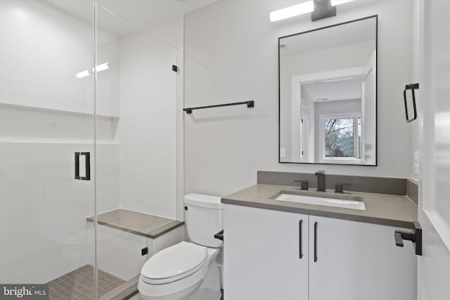 bathroom featuring vanity, a shower with shower door, and toilet