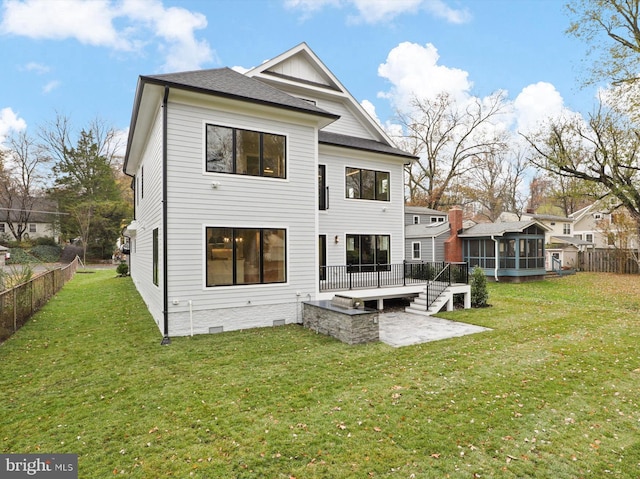 rear view of property featuring a sunroom, a wooden deck, a patio, and a lawn