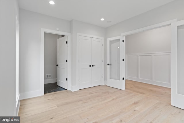 unfurnished bedroom with light hardwood / wood-style flooring and french doors