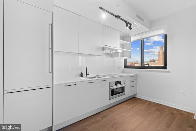 kitchen featuring white cabinets, stainless steel oven, black electric stovetop, and sink