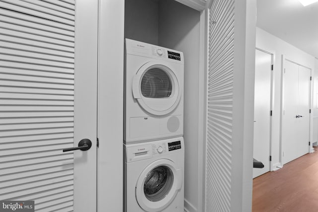 washroom featuring stacked washer / dryer and light hardwood / wood-style floors