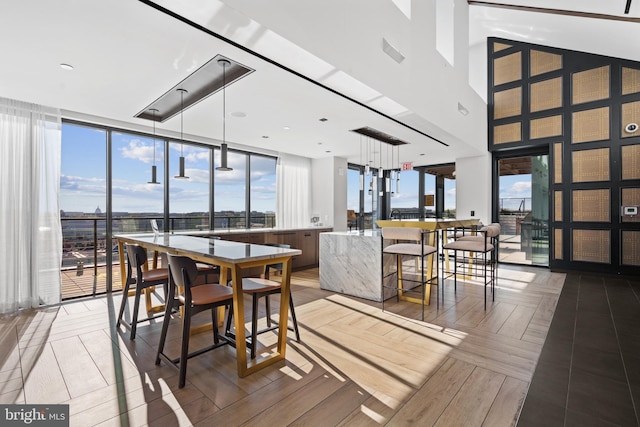 dining area with parquet flooring, plenty of natural light, a high ceiling, and a wall of windows