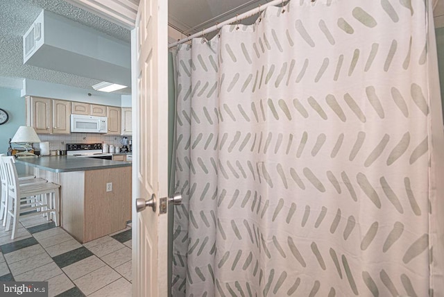 bathroom featuring a textured ceiling, backsplash, and curtained shower