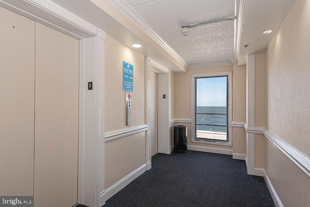 hall with dark colored carpet, a textured ceiling, elevator, and crown molding