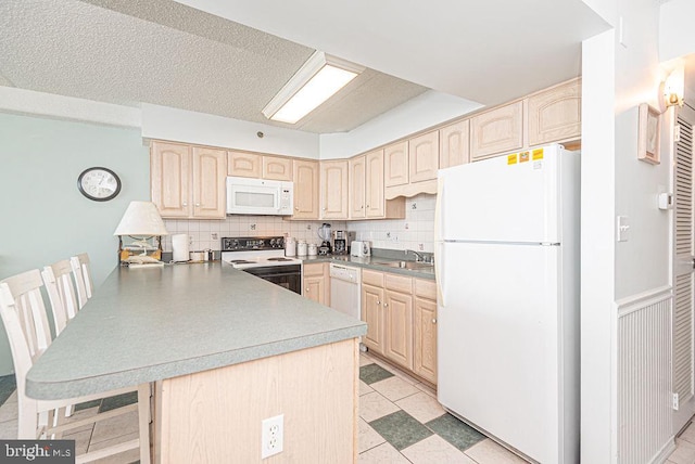 kitchen featuring kitchen peninsula, light brown cabinetry, white appliances, and backsplash