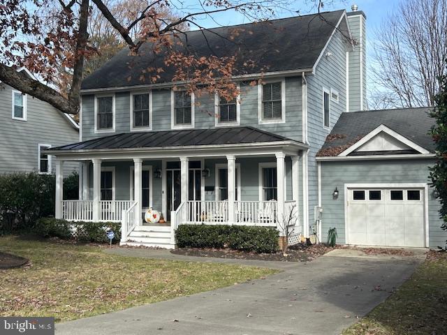 view of front of property with covered porch, a garage, and a front lawn