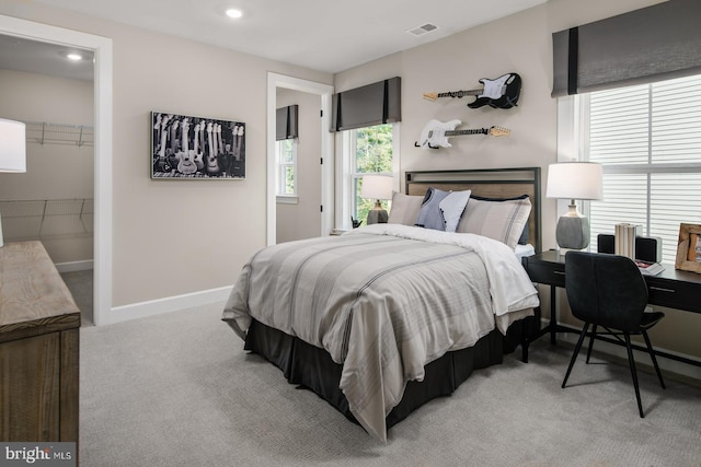 carpeted bedroom featuring a walk in closet and a closet