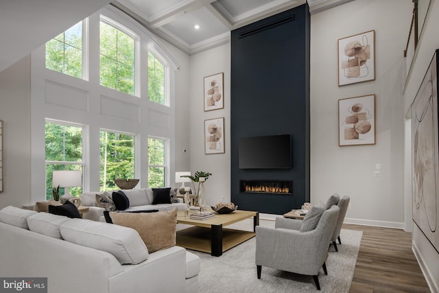 living room with ornamental molding, coffered ceiling, hardwood / wood-style flooring, a fireplace, and a high ceiling