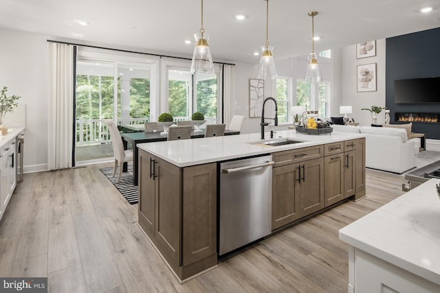 kitchen featuring light stone countertops, dishwasher, pendant lighting, and light hardwood / wood-style floors