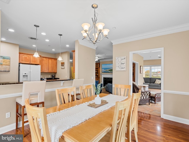 dining space with ornamental molding, light wood-type flooring, and a notable chandelier