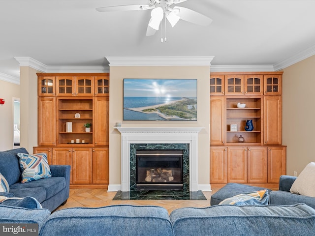 living room with ceiling fan, a premium fireplace, crown molding, and light tile patterned floors