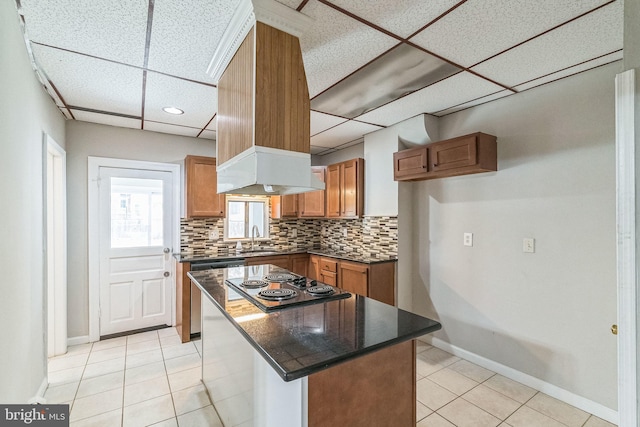 kitchen featuring a drop ceiling, a center island, sink, light tile patterned floors, and appliances with stainless steel finishes