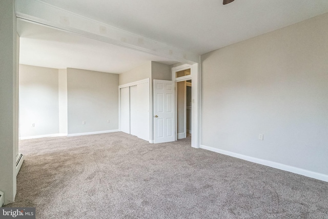 unfurnished room featuring carpet flooring and a baseboard heating unit