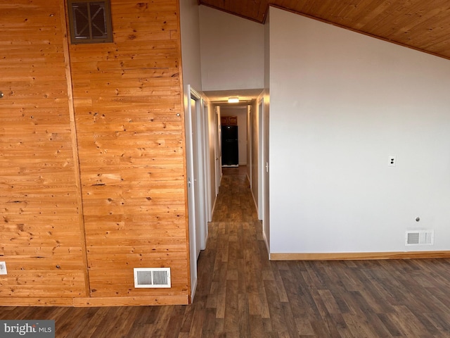 corridor with dark hardwood / wood-style flooring, vaulted ceiling, wood walls, and wood ceiling