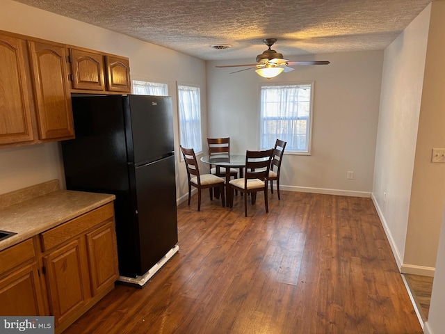 kitchen featuring a textured ceiling, dark hardwood / wood-style floors, black fridge, and ceiling fan