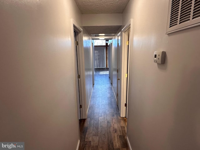 corridor featuring a textured ceiling and dark wood-type flooring