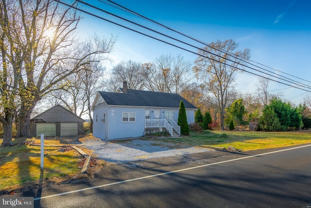 view of front of home featuring a front yard, covered porch, an outdoor structure, and a garage