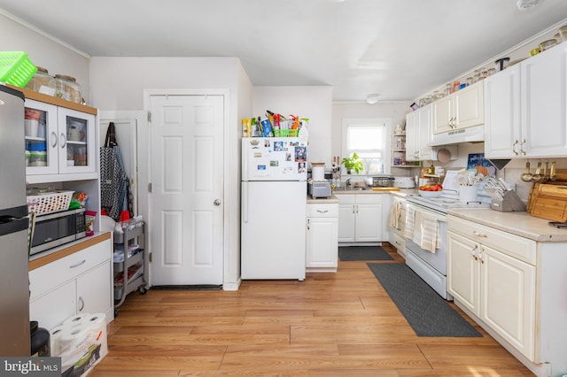 kitchen with sink, white cabinets, white appliances, and light wood-type flooring