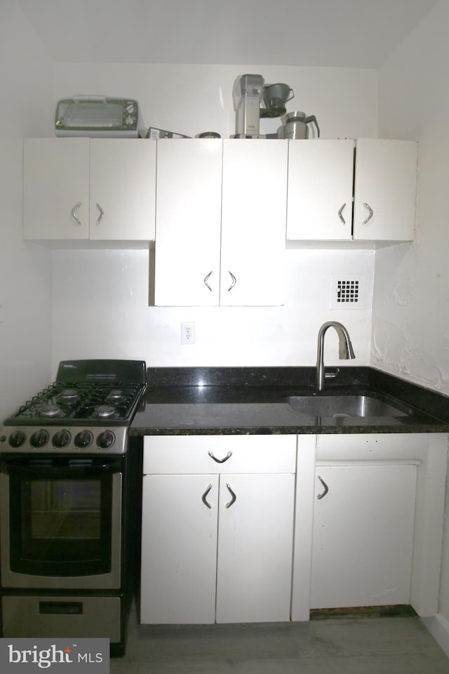 kitchen featuring white cabinetry, stainless steel range with gas cooktop, and sink