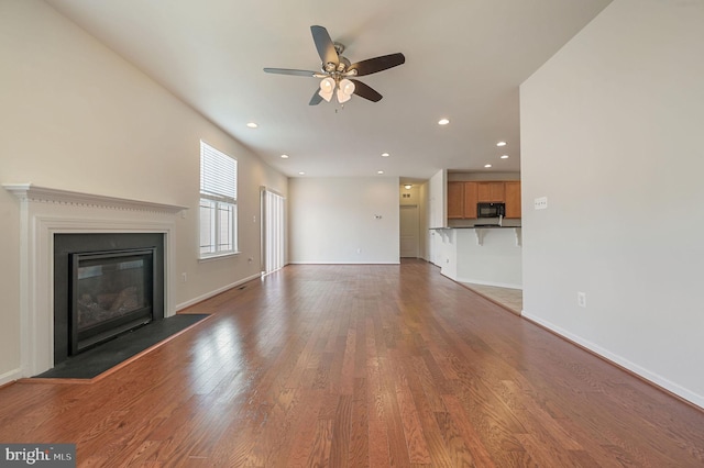 unfurnished living room with dark wood-type flooring and ceiling fan