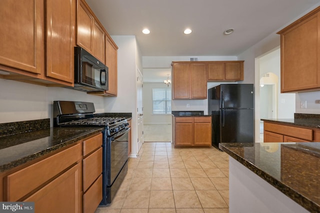 kitchen with dark stone countertops, light tile patterned floors, and black appliances