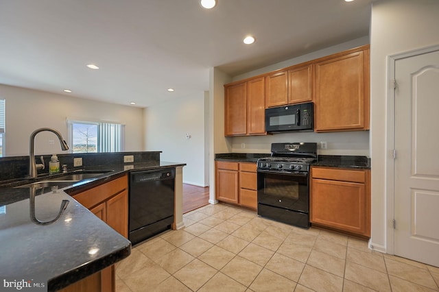 kitchen featuring dark stone countertops, sink, and black appliances