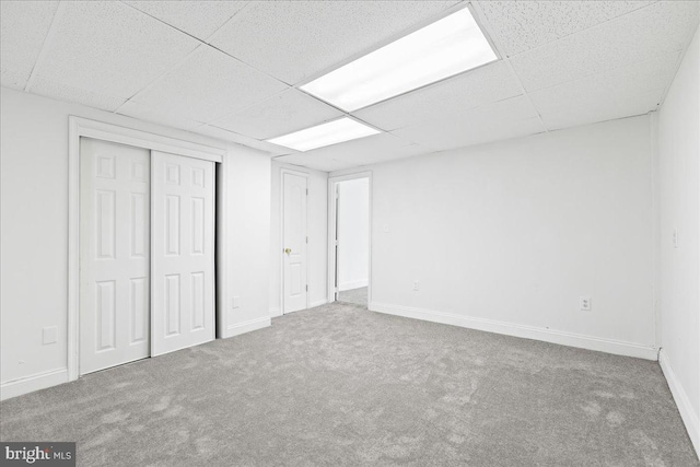 basement featuring carpet flooring and a paneled ceiling